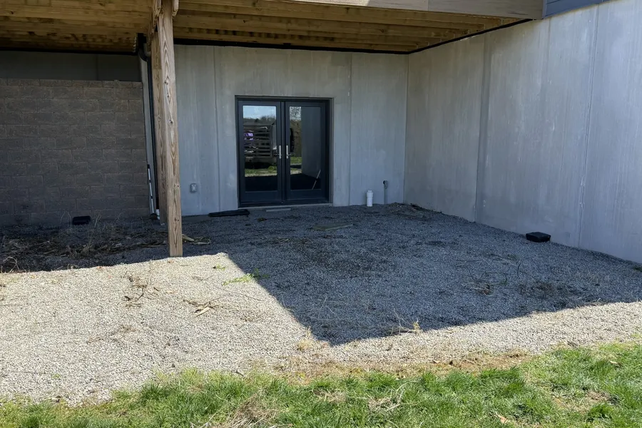 The same gravel patio under the deck, cleared after the trampoline was removed